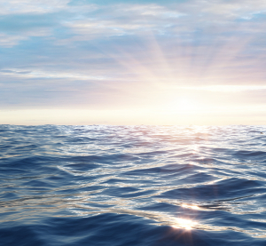 Ruhige Meeresoberfl&auml;che im Sonnenuntergang mit weichem Licht und sanften Wellen.