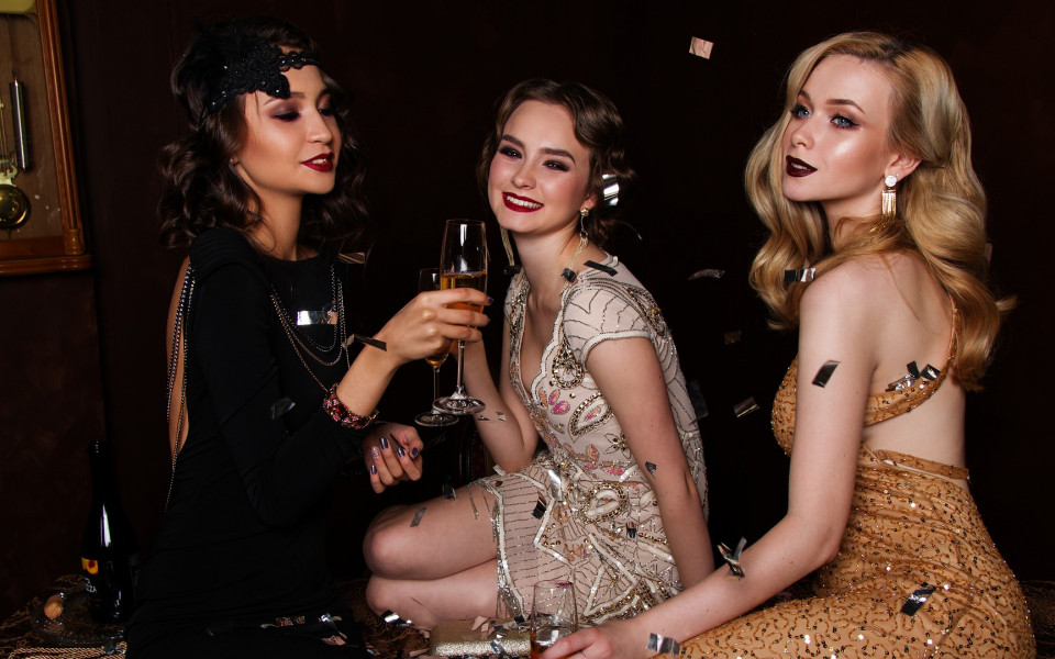 Frauen in Abendkleid mit Sekt und Konfetti