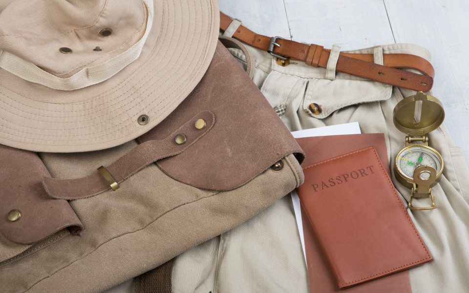 Safari-Ausrüstung: Hut, Rucksack, Kompass und Reisepass für Abenteuer in Afrika.