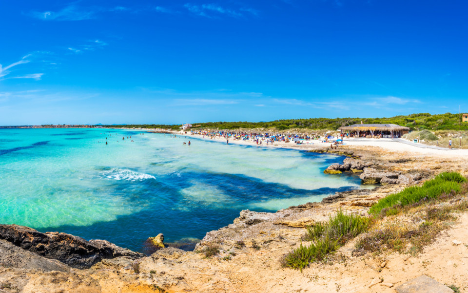 Mallorca Geheimtipp: Strand Playa Es Trenc auf Mallorca mit kristallklarem Wasser, feinem Sand und unber&uuml;hrter Natur unter strahlend blauem Himmel.