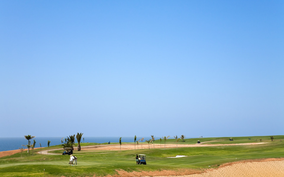 Gr&uuml;ner Golfplatz auf Gran Canaria mit Golfern und Caddy bei strahlend blauem Himmel