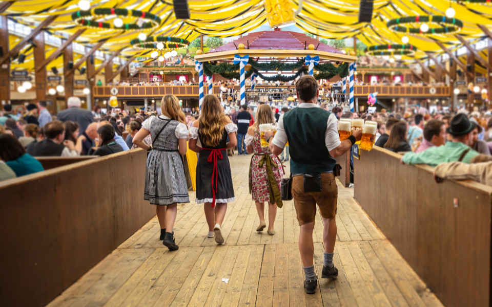 Kellner tragen Ma&szlig; Bier durch ein Festzelt auf dem Oktoberfest in M&uuml;nchen