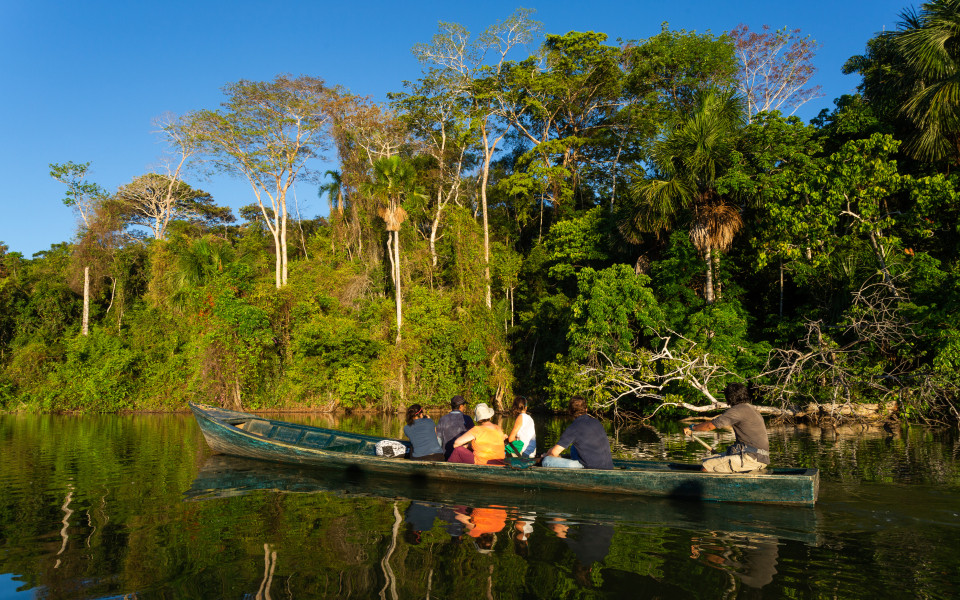 Ein Boot mit Touristen- und Wasserspiegelungen im Amazonas-Dschungel, Puerto Maldonado, Peru