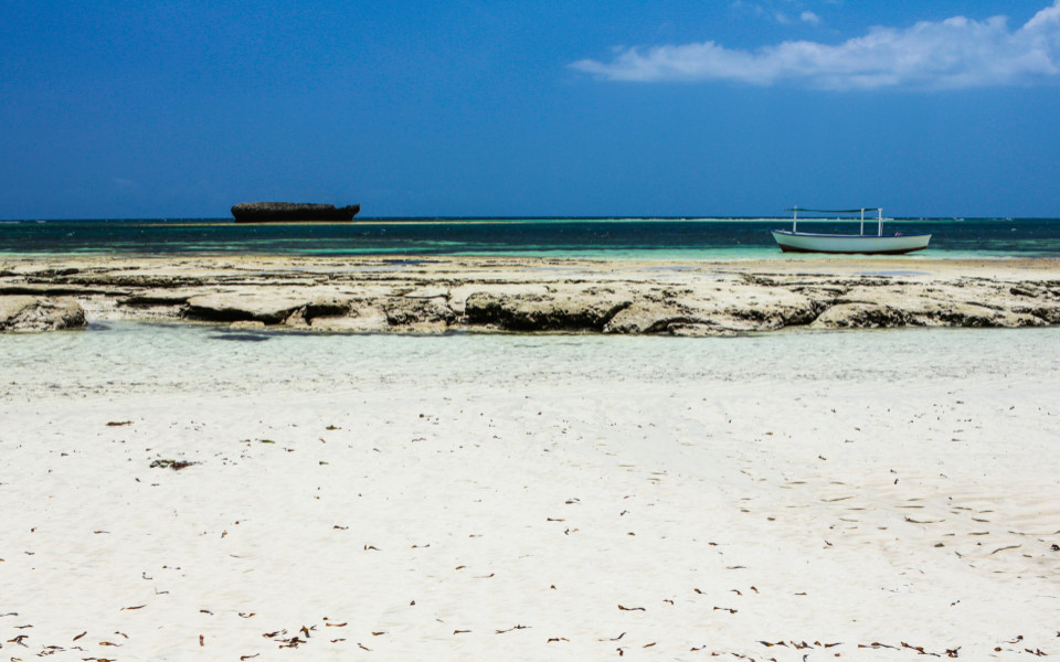 Turtle Bay Beach in Watamu mit wei&szlig;em Sand, klarem Wasser und einem Boot am Ufer.