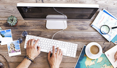 Schreibtisch mit PC, Fotos, Kamera und Landkarten